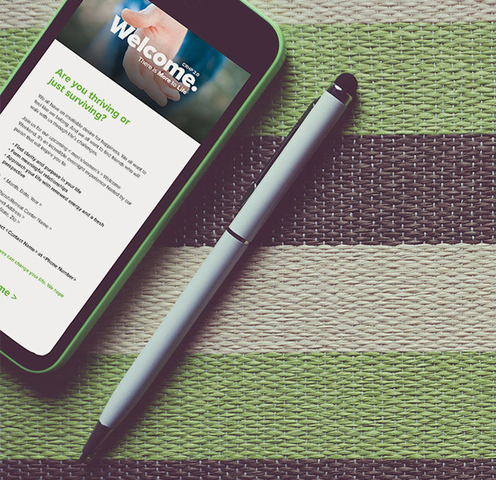 a black iphone with a green phone case and screen that displays an email from the welcome weekend sits on a black, white, and green stripped background next to an open light blue pen