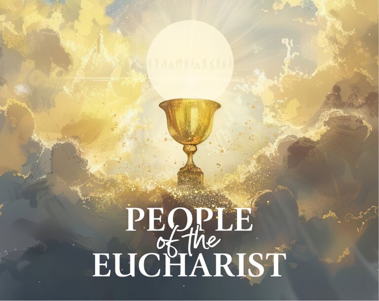 A catholic priest in all white cloaks holds up a chalice and eucharist in his hands during Sunday mass while a deacon stands next to him with his eyes closed and head down