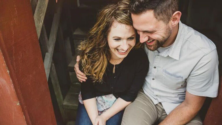 A newly engaged couple sits on the stairs excited to start their life together. 